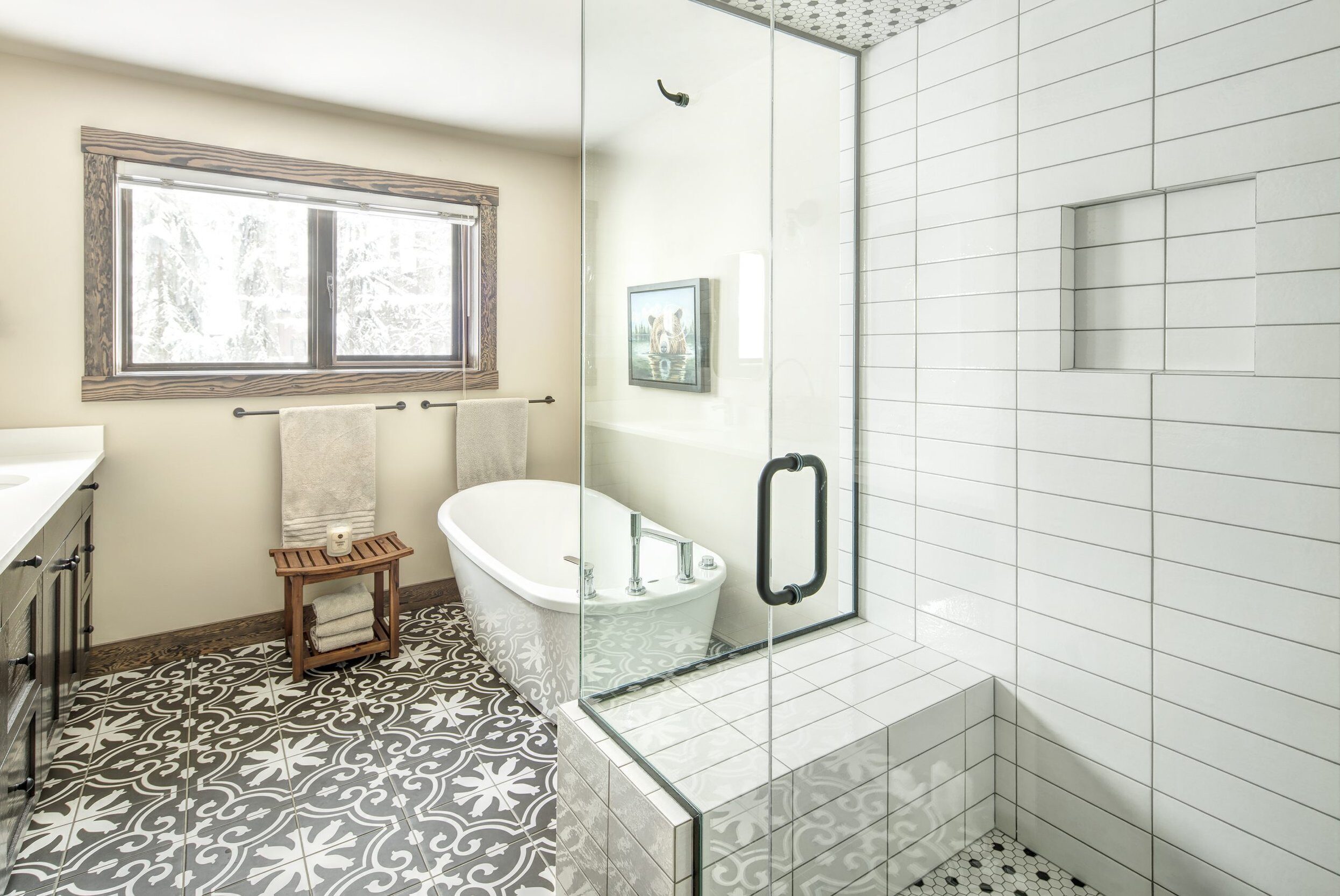 Elegant bathroom featuring custom tile work by Warwick Interiors, including patterned floor tiles, a tiled shower with bench seating, and a freestanding tub, showcasing expert craftsmanship and attention to detail.
