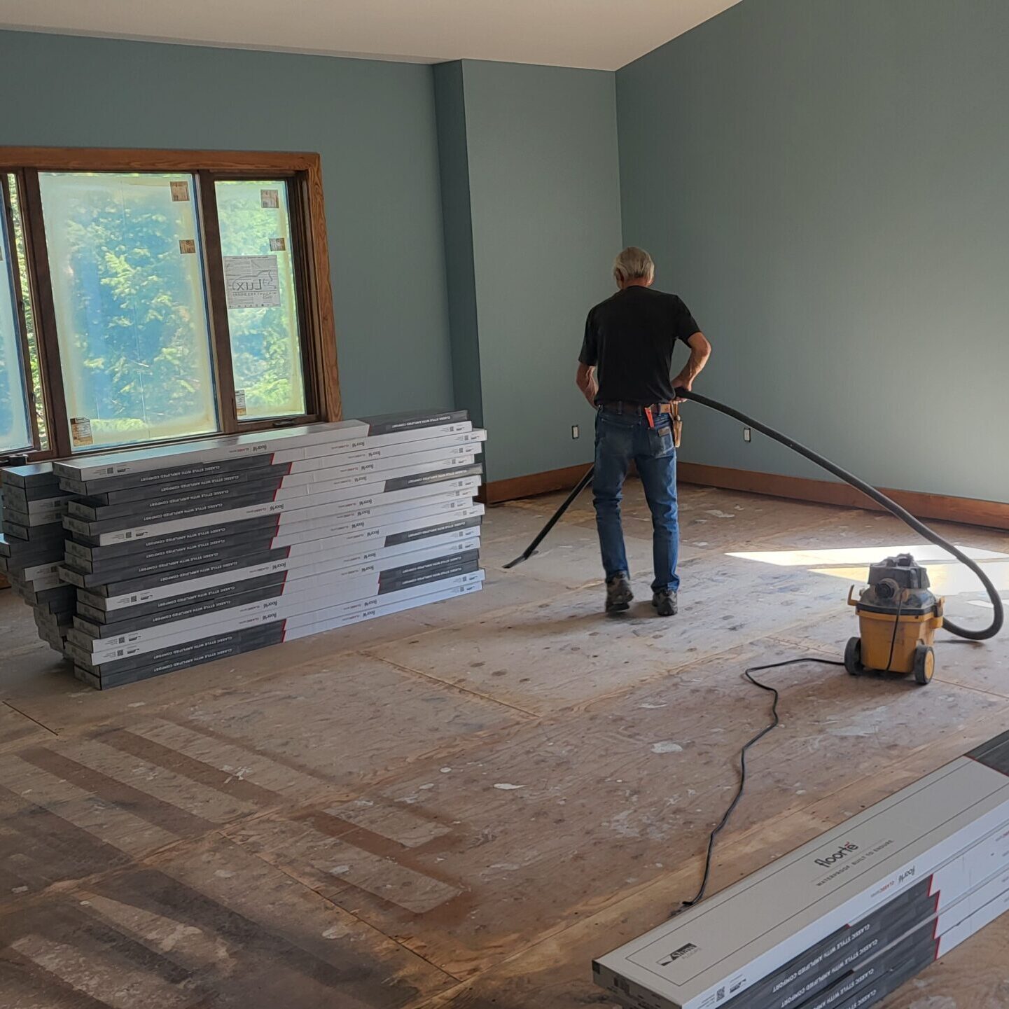 Vacuuming dust and debris after floor sanding to create a clean base for installation. Project by Warwick Interiors in Invermere.
